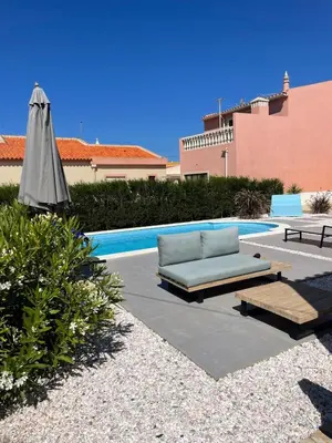 a couch and an umbrella next to a pool at Modern house with private Pool in Sagres