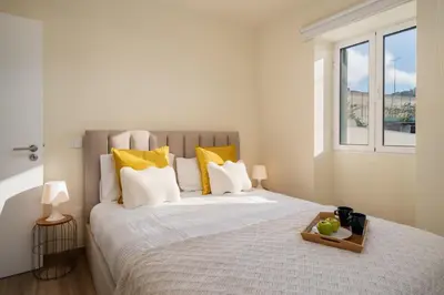 a bedroom with a large bed with yellow pillows at Madeira Friendly Guest House by An Island Apart in Funchal