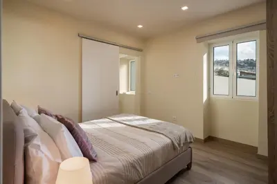 a bedroom with a bed and two windows at Madeira Friendly Guest House by An Island Apart in Funchal