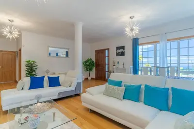 a living room with two white couches and blue pillows at Villa Black Rock by Holiday Rental Madeira in Santa Cruz