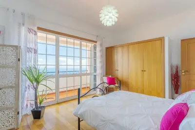 a bedroom with a bed and a window and a chair at Villa Black Rock by Holiday Rental Madeira in Santa Cruz