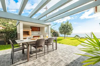 a patio with a table and chairs and a kitchen at Villa Soleil by Homie in Arco da Calheta