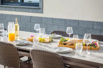 a table with plates of food and wine glasses at Villa Soleil by Homie in Arco da Calheta