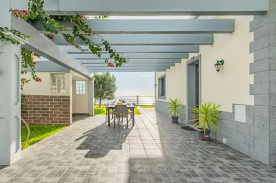 a patio with a pergola with a table and chairs at Villa Soleil by Homie in Arco da Calheta