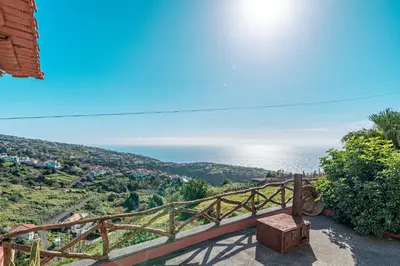 a bedroom with a white bed and a window at Vila Pitaias in Estreito da Calheta