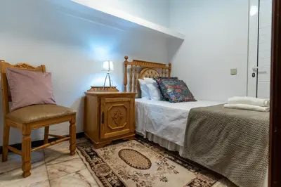 a bedroom with a bed and a chair and a table at Madeira Inn Paradise in Ribeira Brava
