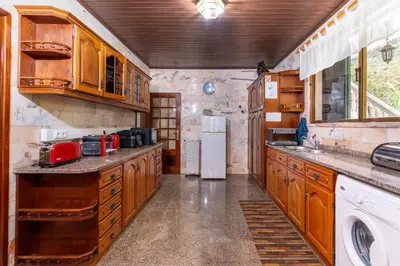 a kitchen with wooden cabinets and a white refrigerator at Madeira Inn Paradise in Ribeira Brava