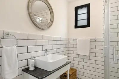 a white tiled bathroom with a sink and a mirror at Casa Francisco in São Vicente