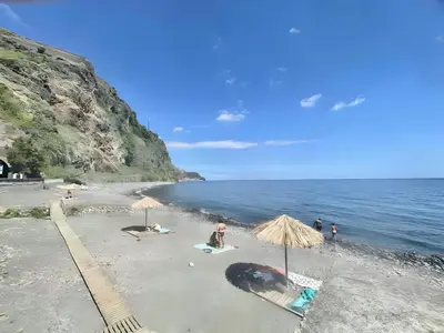 a beach with umbrellas and people on the sand at Casa Orquidea T3 in Ponta do Sol