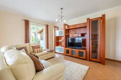 a living room with a white couch and a tv at Villa Pita in Relógio do Poiso