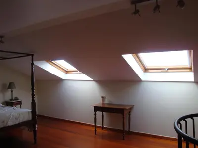 a bedroom with two skylights and a bed and a table at Excelente T3 Duplex Funchal in Funchal