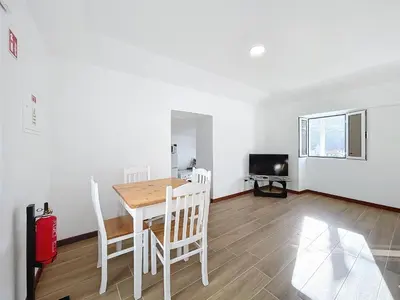 a dining room with a table and chairs and a television at Dinos Sea View in Machico