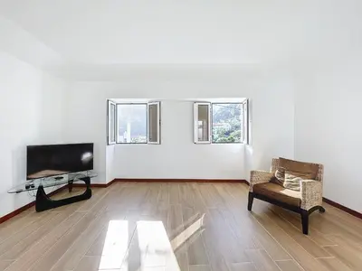 a living room with a flat screen tv and a chair at Dinos Sea View in Machico
