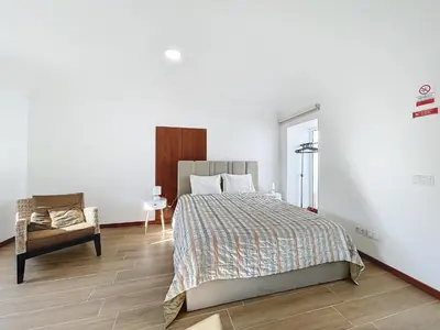 a white bedroom with a bed and a chair at Dinos Sea View in Machico
