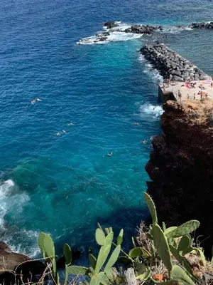 a group of people swimming in the water near a beach at Ocean View Condo in Caniço