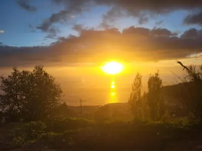 a sunset with the sun setting over the ocean at C&C Sunset Villa in Arco da Calheta