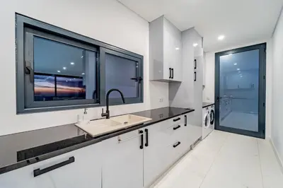 a white kitchen with a sink and two windows at C&C Sunset Villa in Arco da Calheta