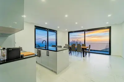 a kitchen and dining room with a view of the ocean at C&C Sunset Villa in Arco da Calheta