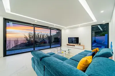 a living room with a blue couch and large windows at C&C Sunset Villa in Arco da Calheta