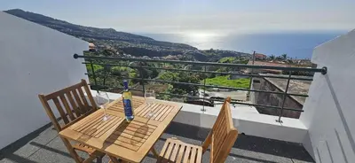 a table and chairs on a balcony with a view of the ocean at Casa Anjinho in Estreito da Calheta