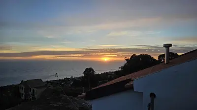 a sunset over the ocean from a house at Casa Anjinho in Estreito da Calheta