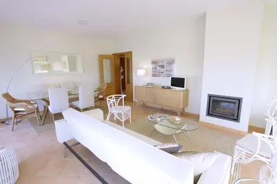 a living room with white furniture and a fireplace at Apartamentos Villa T2 Vila Sagres in Sagres