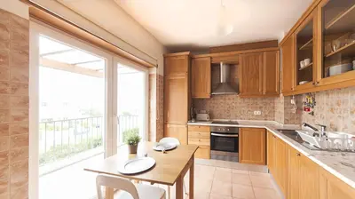 a kitchen with wooden cabinets and a table and a window at Apartamentos Villa T2 Vila Sagres in Sagres