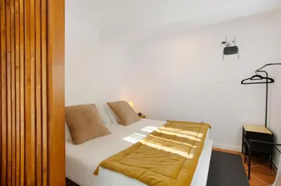 a bedroom with a bed with white sheets and brown pillows at Capelos in Funchal
