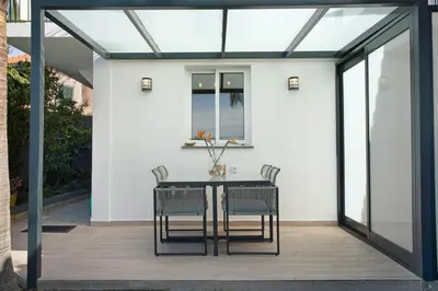 a glass extension of a house with a table and chairs at Capelos in Funchal