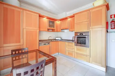 a kitchen with wooden cabinets and a glass table at Casa Clara Sun, Beach and Pool in Lagos