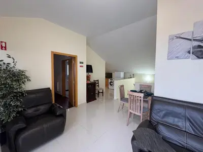a living room with a black leather couch and a kitchen at Prazeres Natura in Prazeres
