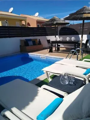 a pool with tables and umbrellas next to a house at Villa Burgau in Lagos
