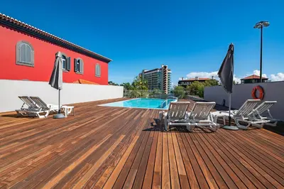 a deck with chairs and umbrellas next to a pool at Luxury Villa Nogueira IV by Holiday Rental Madeira in Funchal