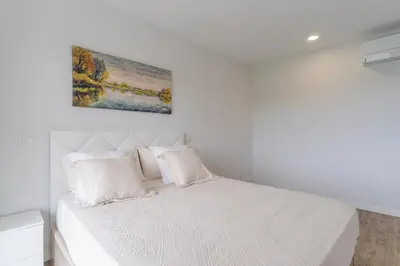 a white bed with two pillows and a painting on the wall at Orquídea Apartment by Holiday Rental Madeira in Funchal