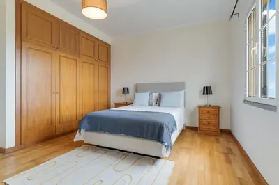 a white bedroom with a bed and a wooden floor at Porto Moniz Yellow House in Porto Moniz
