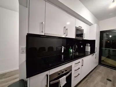 a kitchen with white cabinets and a black counter top at Cliff Residence Ocean View in Gaula