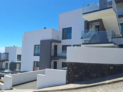 a white apartment building with a stone wall at Cliff Residence Ocean View in Gaula