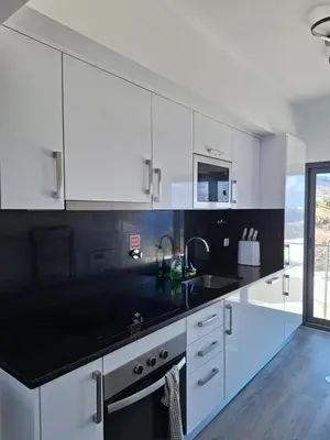 a kitchen with white cabinets and a black counter top at Cliff Residence Ocean View in Gaula