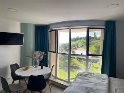a bedroom with a table and a large window at Center Marina view Green Studio in Funchal