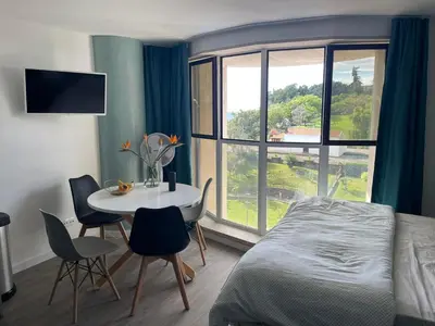 a bedroom with a bed and a table and a window at Center Marina view Green Studio in Funchal