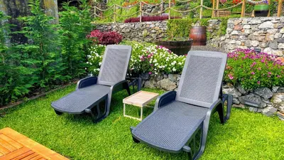 three chairs and a table in a yard with flowers at Casas das Hortas, Studio Vista Jardim e Serra in Seixal