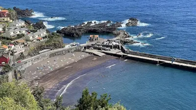 a bridge over a beach with people in the water at Casas das Hortas, Studio Vista Jardim e Serra in Seixal