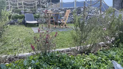 a garden with a table and chairs and flowers at Casas das Hortas, Studio Vista Jardim e Serra in Seixal