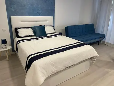 a bedroom with a large bed and a blue chair at Center Marina view Blue Studio in Funchal