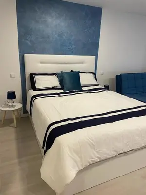 a bedroom with a large white bed with a blue wall at Center Marina view Blue Studio in Funchal