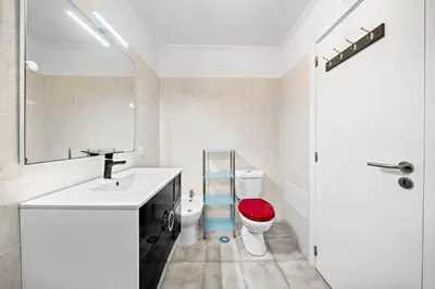 a bathroom with a sink and a toilet with a red seat at Petit Campanário in Campanário