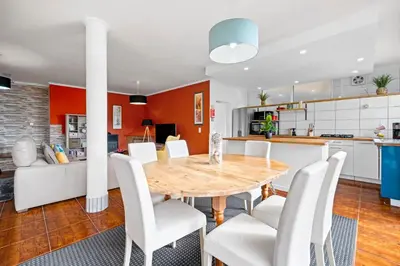 a kitchen and dining room with a wooden table and white chairs at Petit Campanário in Campanário