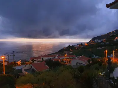 a view of a town and the ocean at night at Villa Palmera Sea View in Arco da Calheta
