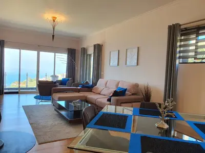 a living room with a couch and a table at Villa Palmera Sea View in Arco da Calheta