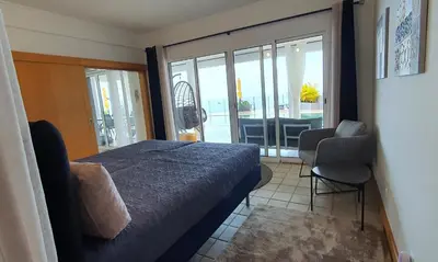 a bedroom with a bed and a view of a balcony at Villa Palmera Sea View in Arco da Calheta